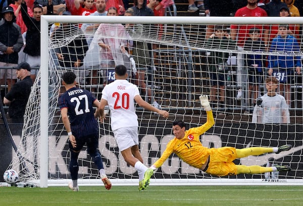 Turkey goalie Berke Özer (12) dives for but can't make the save on a goal by United States midfielder Jack McGlynn as United States defender Max Arfsten (27) and Turkey forward Oguz Aydin (20) look on during the first half of an international friendly soccer game, Saturday, June 7, 2025, in East Hartford, Conn. (AP Photo/Mary Schwalm)