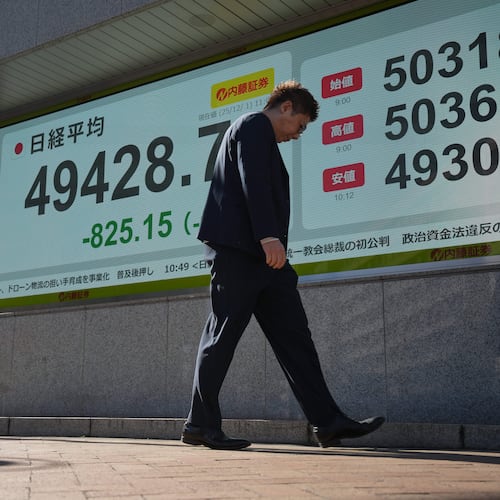 A person walks in front of an electronic stock board showing Japan's Nikkei index at a securities firm Monday, Dec. 1, 2025, in Tokyo. (AP Photo/Eugene Hoshiko)