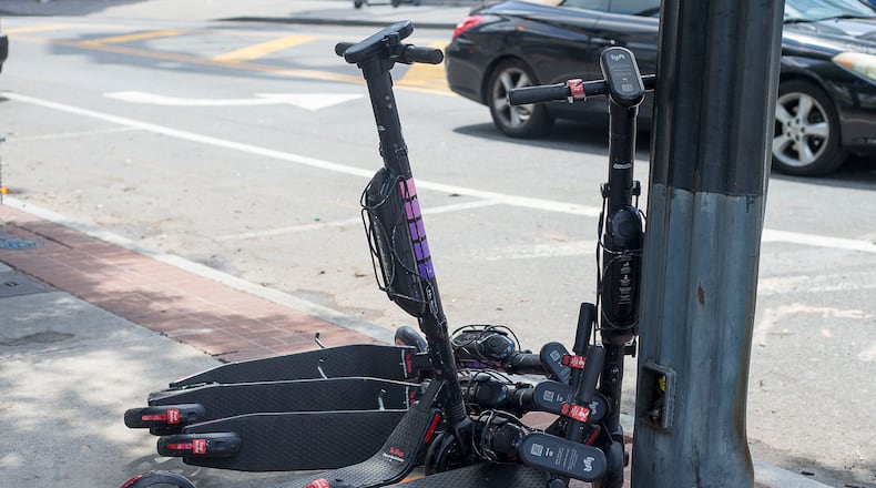 Electric scooters sit piled up on the sidewalk near Centennial Olympic Park in Atlanta. (Alyssa Pointer/alyssa.pointer@ajc.com)