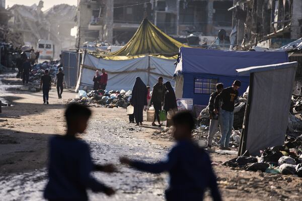 Displaced Palestinians carry water next to destructions in Jabaliya, Gaza Strip on Monday, March 31, 2025. (AP Photo/Jehad Alshrafi)