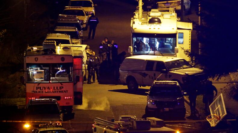 Law enforcement officers stand by command vehicles on East 52nd Street in Tacoma, Wash., in the early hours of Thursday, Dec. 1, 2016, near the home where a Tacoma Police officer was fatally shot Wednesday. The police officer who was shot multiple times while responding to a domestic violence call died Wednesday night, while police worked to arrest a suspect they believed was still barricaded in the home with a gun, authorities said. (AP Photo/Ted S. Warren)