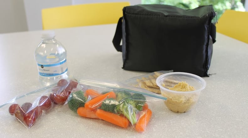 A healthy lunch of hummus, whole-wheat crackers, grapes and bottled water. School lunches ought to provide every student with good nutrition to keep them healthy and learning.