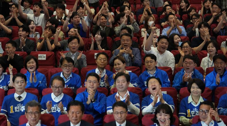 Lawmakers and members of South Korea's ruling Democratic Party react as they watch TV news program about results of exit polls for June 3 nationwide simultaneous local elections at the National Assembly in Seoul, South Korea, Wednesday, June 3, 2026. (AP Photo/Lee Jin-man)