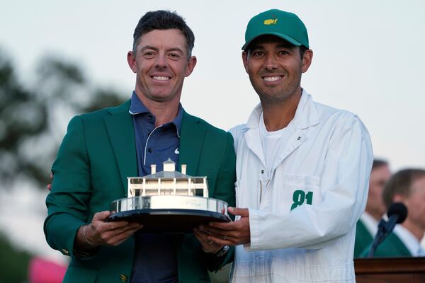 Rory McIlroy, of Northern Ireland, holds the trophy with caddie Harry Diamond after winning the Masters golf tournament, Sunday, April 13, 2025, in Augusta, Ga. (AP Photo/Ashley Landis)