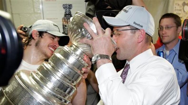 FILE - In this June 12, 2009, file photo, Pittsburgh Penguins' captain Sidney Crosby, left, helps Pittsburgh Penguins head coach Dan Bylsma drink champagne from the Stanley Cup after the Penguins beat the Detroit Red Wings 2-1 to win Game 7 of the NHL hockey Stanley Cup finals, in Detroit. Michael Schuckers, a statistics professor at St. Lawrence University in northern New York, said it�s also difficult to gauge the impact of a coach, unless there�s something like a team that�s relatively static and the only change made is the coach. �When the Penguins won the Stanley Cup, you can look at how the Penguins were under (current Montreal Canadiens coach Michel) Thierren (27-25-5) and under (Dan) Bylsma (18-3-4),� Schuckers said. �It's a clear break in terms of the team playing much better under Bylsma.� (AP Photo/Paul Sancya, File)
