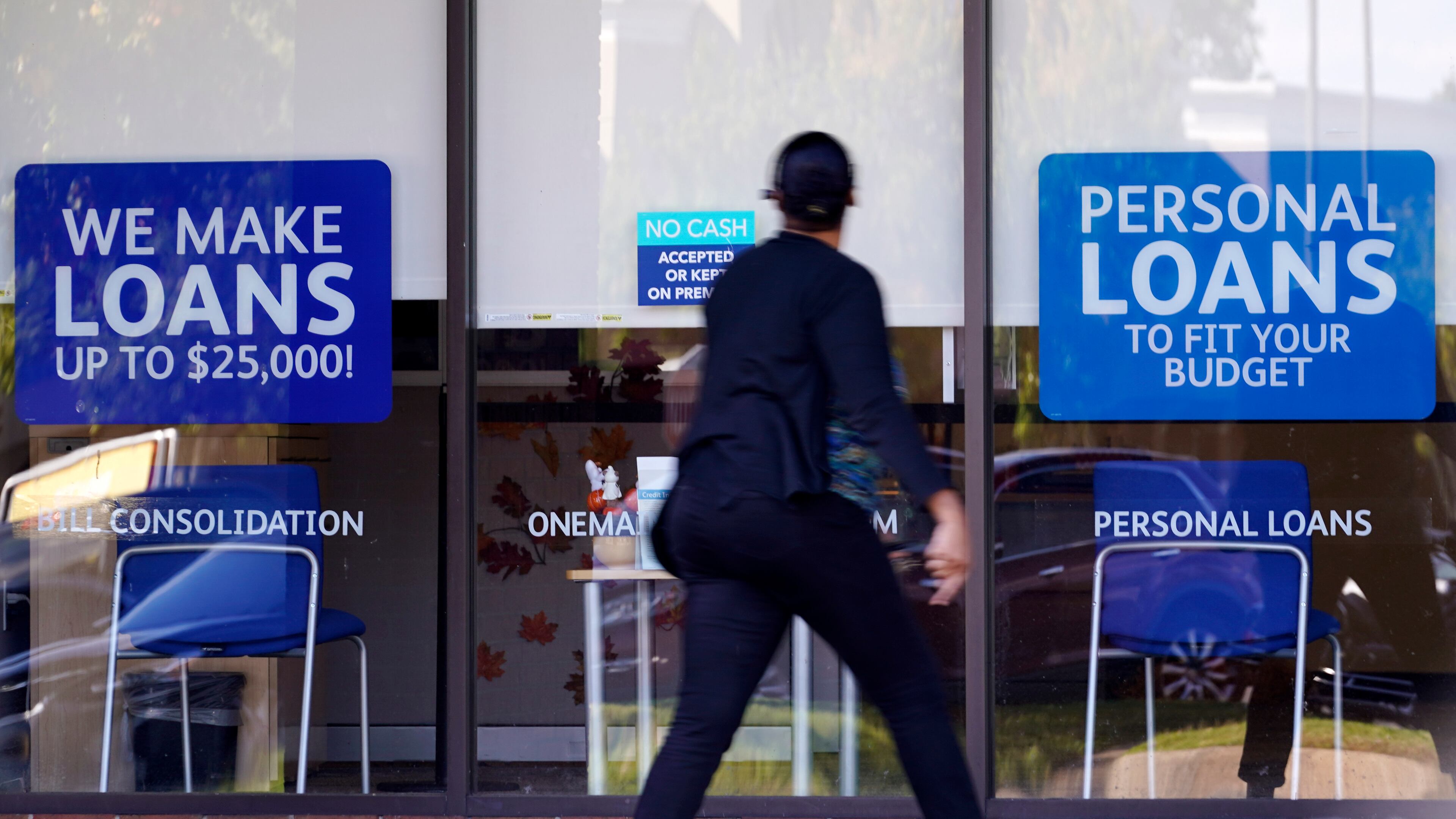FILE - A woman walks past a personal finance loan office Thursday, Oct. 1, 2020, in Franklin, Tenn. (AP Photo/Mark Humphrey, File)