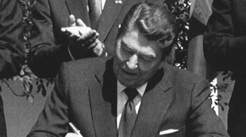 FILE - President Ronald Reagan signs legislation implementing the U.S.-Canada free trade agreement during a ceremony at the White House, Sept. 28, 1988. (AP Photo/Scott Stewart, File)