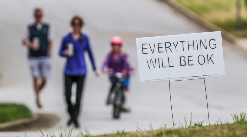 Matt Blackburn, Shannon Blackburn, 4-year-old Jackson and 7-year-old Henley walk past one of several "Everything will be OK" yard signs along Trailridge Lane in Dunwoody. JOHN SPINK/JSPINK@AJC.COM