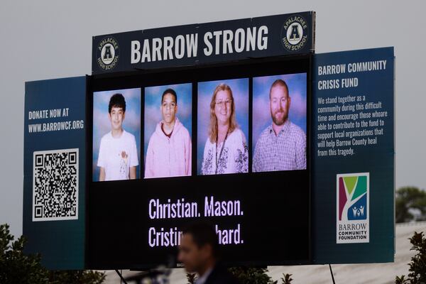 An electronic billboard showing 14-year-old Apalachee High School students Christian Angulo and Mason Schermerhorn, and teachers Cristina Irimie and Richard Aspinwall, is seen during a vigil at Jug Tavern Park in Winder on Friday, Sept. 6, 2024. (Arvin Temkar/AJC)