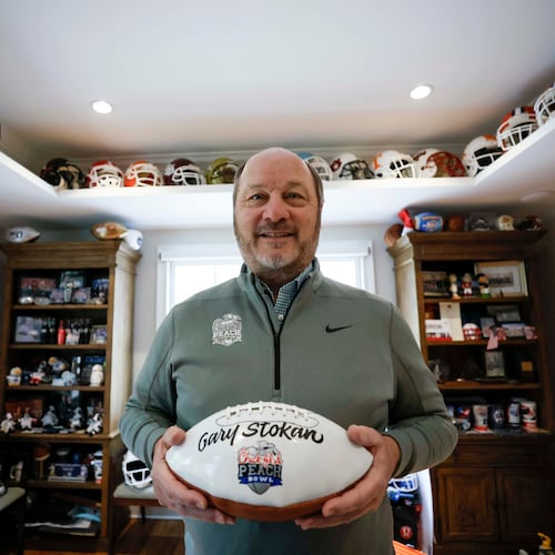 Gary P. Stokan, CEO and president of the Peach Bowl, poses with a Peach Bowl football bearing his name at his Atlanta home on Wednesday, Dec. 17, 2025. Stokan has positioned the Peach Bowl as one of the nation’s top bowl game organizations, and he is set to retire after his final Peach Bowl on Jan. 9, 2026. (Miguel Martinez/ AJC)