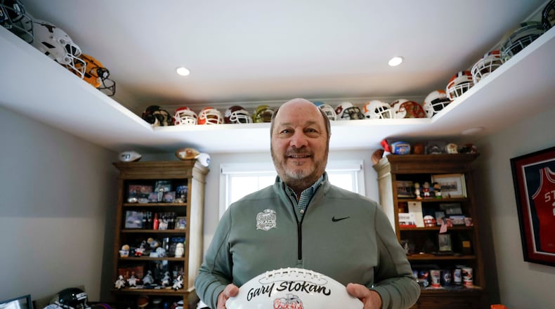 Gary P. Stokan, CEO and president of the Peach Bowl, poses with a Peach Bowl football bearing his name at his Atlanta home on Wednesday, Dec. 17, 2025. Stokan has positioned the Peach Bowl as one of the nation’s top bowl game organizations, and he is set to retire after his final Peach Bowl on Jan. 9, 2026. (Miguel Martinez/ AJC)