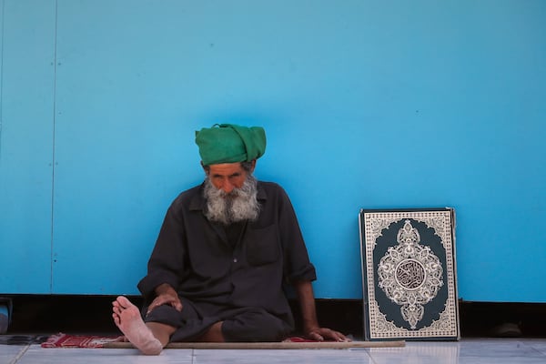 A man sits next to a copy of the Quran at the Sayyida Zeinab Shrine, where many Shiite Muslims believe Zeinab, the granddaughter of Prophet Muhammad, is entombed, in Sayyida Zeinab, south of Damascus, Syria, Saturday, March 15, 2025. (AP Photo/Omar Sanadiki)
