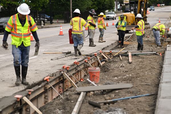 Precision 2000 Inc. construction workers pave a sidewalk for the Howell Mill Complete Street Project on Thursday, May 21, 2026. The Atlanta-based civil construction company has helped shape the region. (Natrice Miller for the AJC)