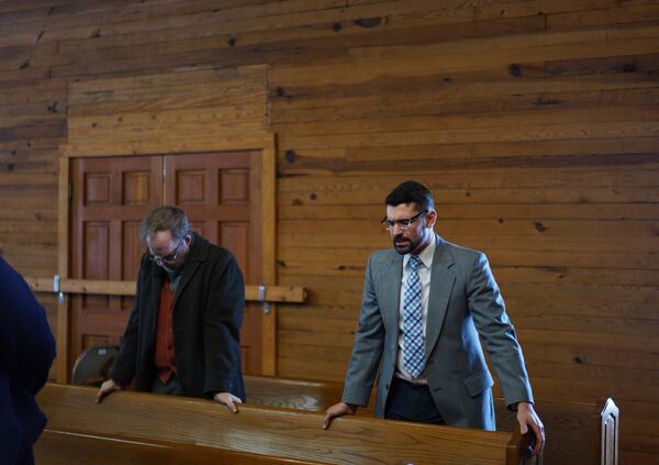 Matt Hinton, left, bows his head as Shane Brown, right, leads a group of Sacred Harp singers in prayer at Holly Springs Primitive Baptist Church in Bremen, Ga., on Sunday, March 23, 2025. (AP Photo/Jessie Wardarski)