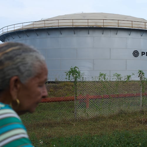 A woman walks near of a oil storage tank of Venezuela's state-run oil company, PDVSA in Cabimas, Venezuela, Tuesday, Sep. 1, 2026. (AP Photo/Ariana Cubillos)