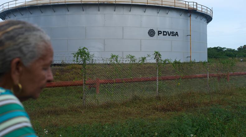 A woman walks near of a oil storage tank of Venezuela's state-run oil company, PDVSA in Cabimas, Venezuela, Tuesday, Sep. 1, 2026. (AP Photo/Ariana Cubillos)