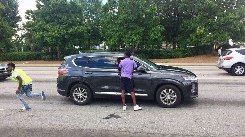 Quanarius Hosch, 15, hurries to get another bottle of water before the light changes at the corner of Northside Drive and Joseph E. Boone Blvd. Photo by BILL TORPY
