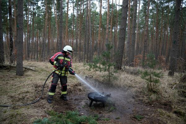 A firefighter extinguishes a fire during a presentation of a prototype AI-based drone system with an autonomous Al-based system for early detection of forest fires by Dryad Networks, in Eberswalde, eastern Germany, Thursday, March 27, 2025. (AP Photo/Ebrahim Noroozi)