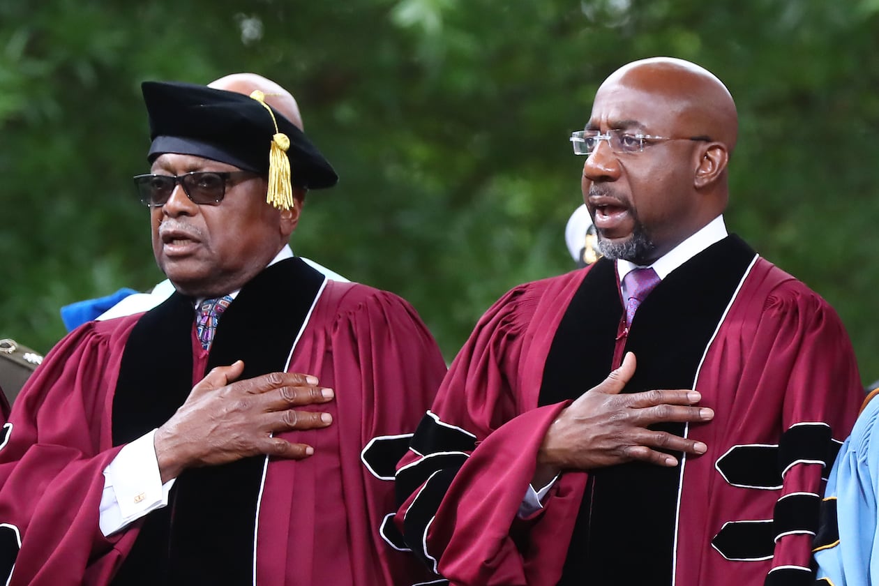 Rep. James E. Clyburn (left) of South Carolina, who received the Honorary Doctor of Laws degree, and Sen. Raphael G. Warnock (right), of Georgia, who received the Honorary Doctor of Humane Letters degree and also deliverd the commencement address, put their hands on their hearts for the presentation of colors and "The Star-Spangled Banner" during the Morehouse College 138th Commencement Ceremony on Sunday, May 15, 2022, in Atlanta. (Curtis Compton/AJC)