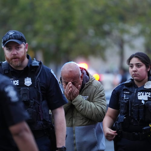 An unidentified man is led into the scene by police after they responded to a shooting at Seattle Center during the Bite of Seattle food festival Sunday, July 26, 2026, in Seattle, Wash. (AP Photo/Lindsey Wasson)