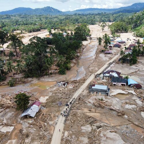 People walk along a road in a village affected by a flash flood in Batang Toru, North Sumatra, Indonesia, Monday, Dec. 1, 2025. (AP Photo/Binsar Bakkara)