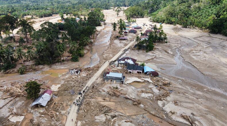People walk along a road in a village affected by a flash flood in Batang Toru, North Sumatra, Indonesia, Monday, Dec. 1, 2025. (AP Photo/Binsar Bakkara)