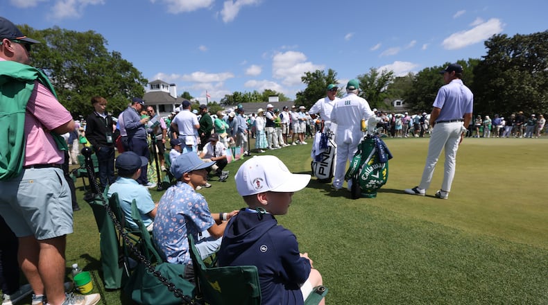 Boys sits inside the ropes watching golfers use the practive putting green, during third round of the Masters golf tournament, at Augusta National Golf Club, Saturday, April 12, 2025, in Augusta, Ga. (Jason Getz / AJC)