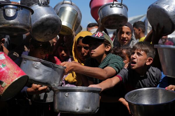 Palestinians struggle to get donated food at a community kitchen in Khan Younis, southern Gaza Strip, Monday, June 2, 2025. (AP Photo/Abdel Kareem Hana)