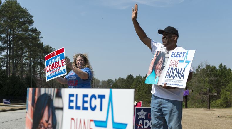 Jim Yates, right, and Shelia Messamore, left, wave to passing cars outside the polling station at New Birth Missionary Baptist Church in Atlanta in March. Candidates for local offices file campaign reports to their local jurisdiction, a process that can make it harder for citizens to access them. (DAVID BARNES / DAVID.BARNES@AJC.COM)