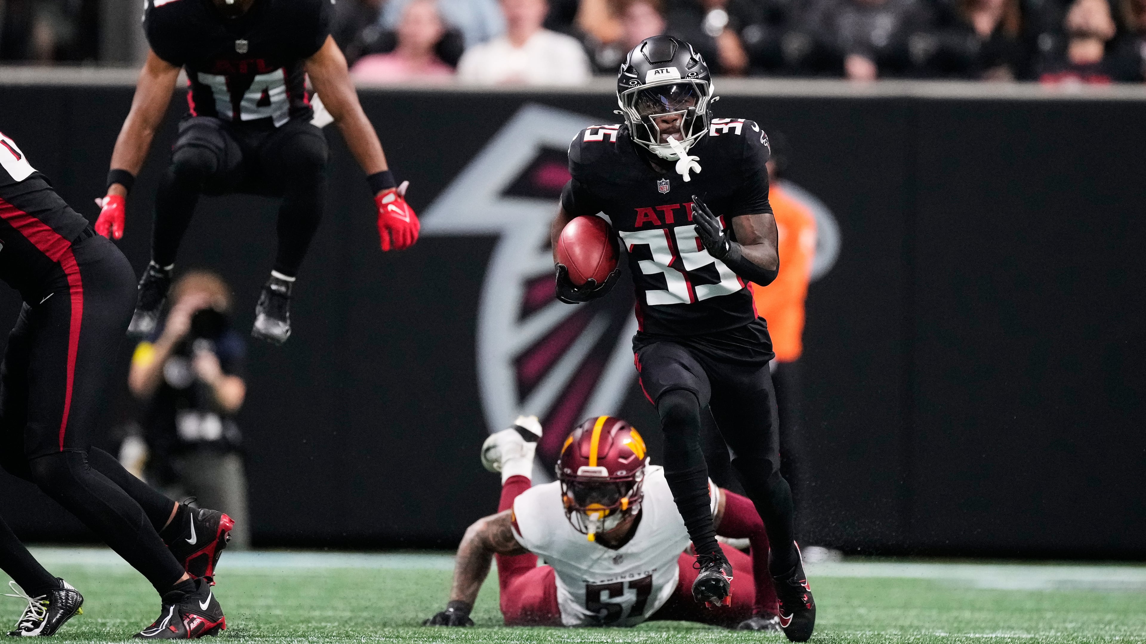 The Falcons' Natrone Brooks (center) runs the ball past the Commanders' Nick Bellore during the first half Sunday, Sept. 28, 2025, in Atlanta. Brooks suffered a concussion after a helmet-to-helmet hit and left the game. (Brynn Anderson/AP)