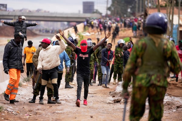 Demonstrators gesture to anti-riot police during the historic 1990 "Saba Saba", a Swahili word that means seven seven, protests for democratic reforms in the Kangemi slum of Nairobi, Kenya Monday, July 7, 2025. (AP Photo/Brian Inganga)