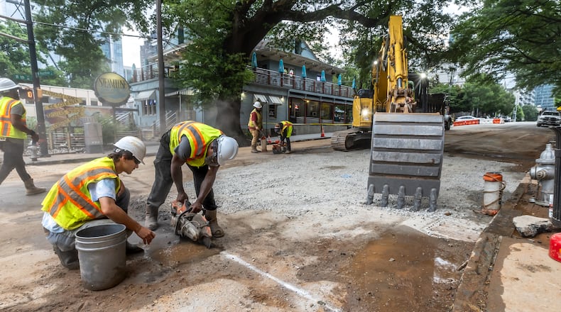 Workers continued to put the finishing touches on the filled in water main hole Wednesday morning, June 5, 2024 following the city’s announcement that water had been restored following the break on West Peachtree Street and 11th Street. The city said the system was being brought back online slowly to “allow system pressures to build.” (John Spink/AJC)