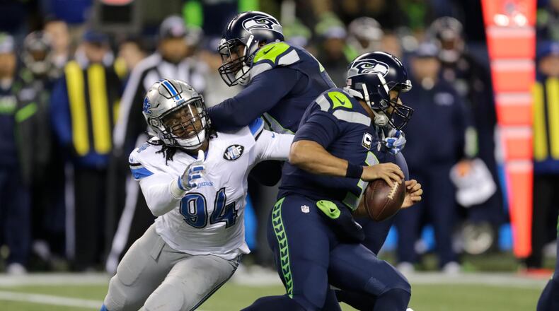 Seattle Seahawks quarterback Russell Wilson, right, is pursued by Detroit Lions defensive end Ezekiel Ansah (94) as Ansah is blocked by Seattle Seahawks offensive tackle George Fant, center, in the first half of an NFL football NFC wild card playoff game, Saturday, Jan. 7, 2017, in Seattle. (AP Photo/Stephen Brashear)