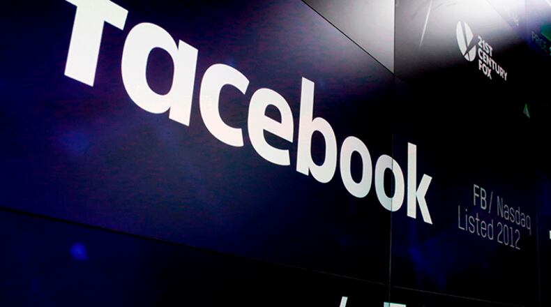The logo for Facebook appears on screens at the Nasdaq MarketSite in New York's Times Square. iPhone users are reporting on social media that Facebook might be using their smartphone cameras without their knowledge while scrolling through the app's news feed.