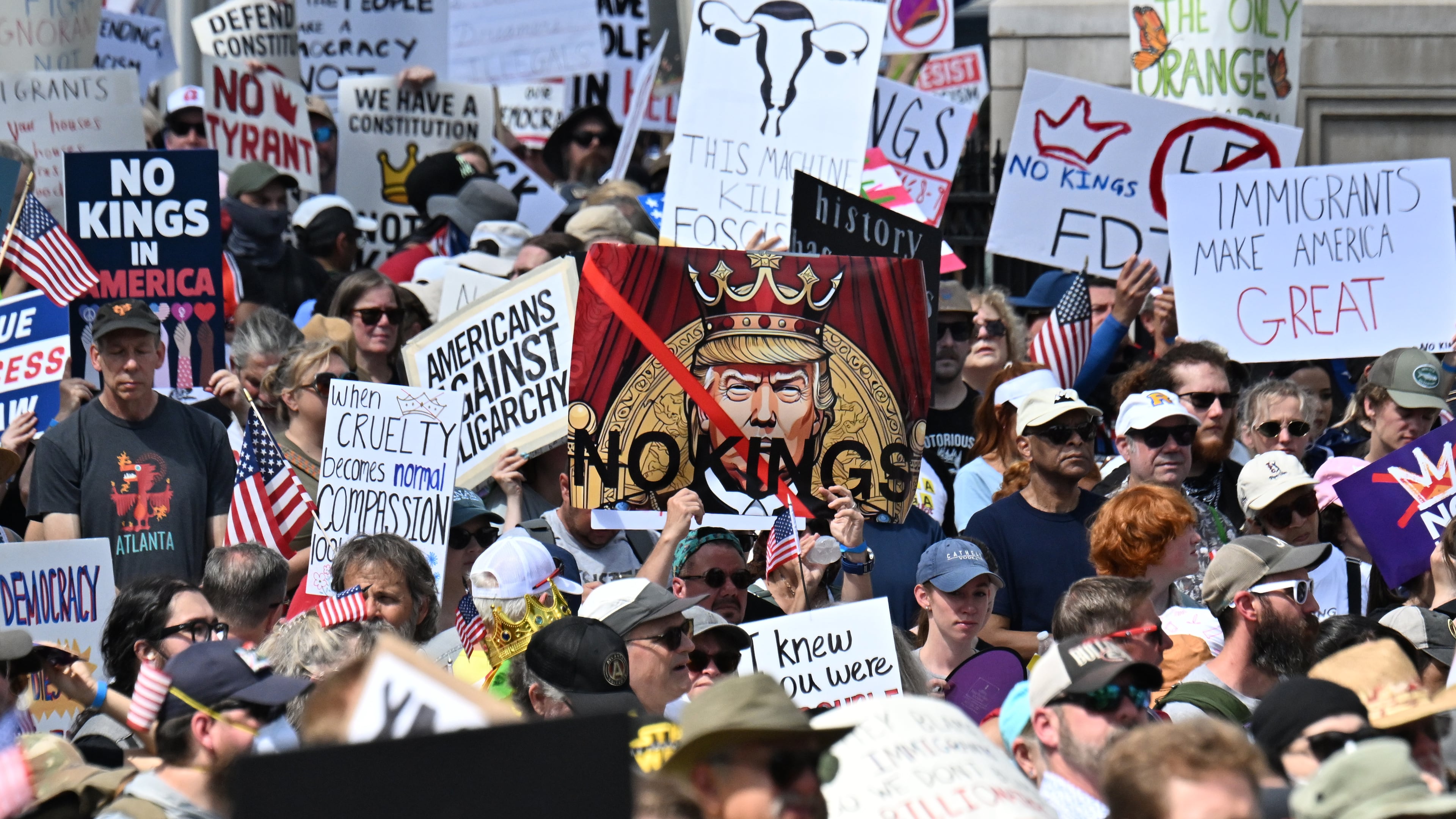 Demonstrators hold signs at Liberty Plaza, near the Georgia Capitol, for a "No Kings" protest to oppose Trump’s immigration policies, Saturday, June 14, 2025, in Atlanta. (Hyosub Shin/AJC)