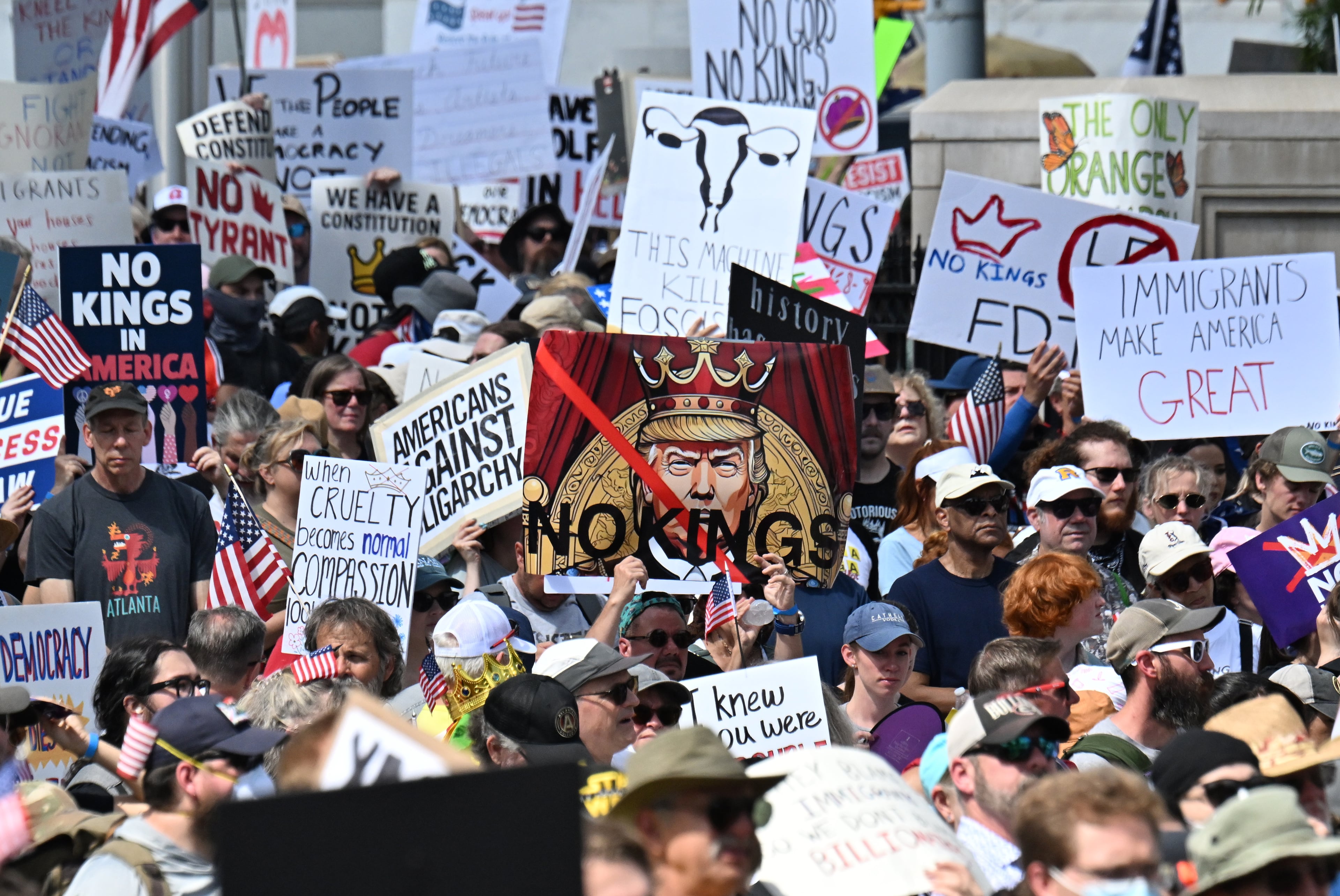 Demonstrators hold signs at Liberty Plaza, near the Georgia Capitol, for a "No Kings" protest to oppose Trump’s immigration policies, Saturday, June 14, 2025, in Atlanta. (Hyosub Shin / AJC)