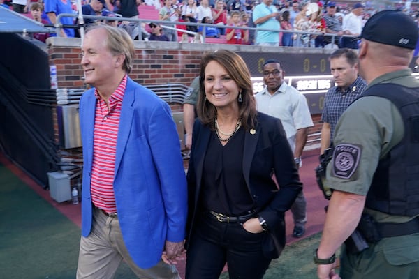 FILE - Texas Attorney General Ken Paxton, left, walks with his wife and Texas State Sen. Angela Paxton on the sideline before an NCAA college football game between Navy and SMU in Dallas, Oct. 14, 2022. (AP Photo/LM Otero, File)