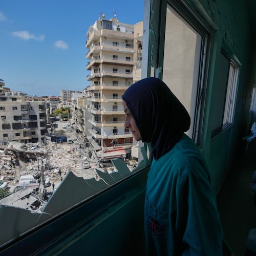 A nurse looks through a shattered window of the Jabal Amel Hospital into a destroyed building that was hit Monday in an Israeli airstrike, in the southern port city of Tyre, Lebanon, Tuesday, June 2, 2026. (AP Photo/Mohammed Zaatari)