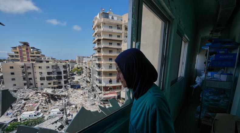 A nurse looks through a shattered window of the Jabal Amel Hospital into a destroyed building that was hit Monday in an Israeli airstrike, in the southern port city of Tyre, Lebanon, Tuesday, June 2, 2026. (AP Photo/Mohammed Zaatari)