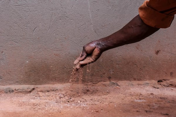 Simon Tigawalana shows dirt, that used to make up his home’s floor, before getting a clay-based earthen floor by a company called EarthEnable on May 16, 2025, in Jinja, Uganda. (AP Photo/Hajarah Nalwadda)