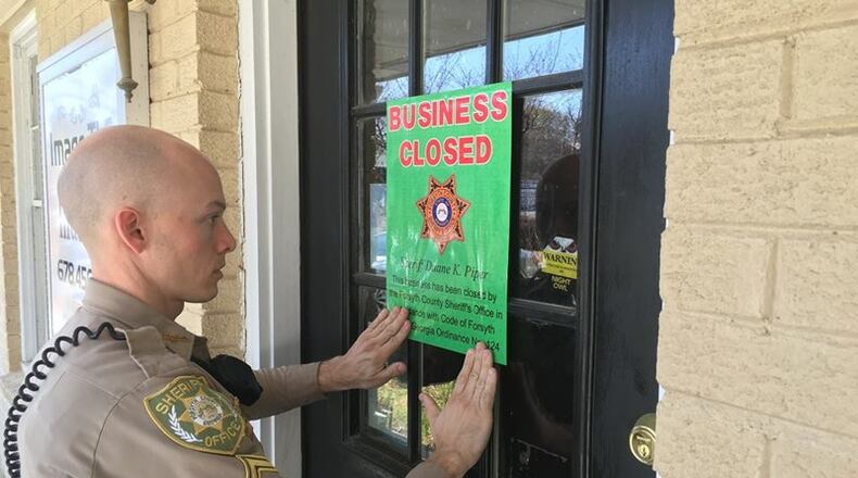 A Forsyth County deputy puts a closure notice up at one of two Forsyth County massage parlors shut down under the county ordinance that took effect early last year. CONTRIBUTED
