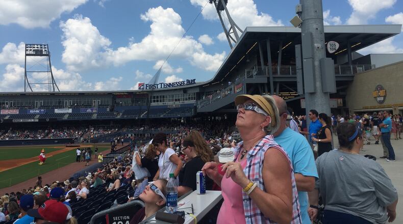 Mary Herrington of Memphis, Tenn. takes in the start of the total solar eclipse in Nashville at First Tennessee Park.
