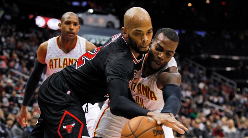 Chicago Bulls forward Taj Gibson, left, reaches for a loose ball with Atlanta Hawks forward Paul Millsap (as Al Horford watches during the second half of an NBA basketball game Friday, Feb. 26, 2016, in Atlanta. Atlanta won 103-88. (AP Photo/Brett Davis)