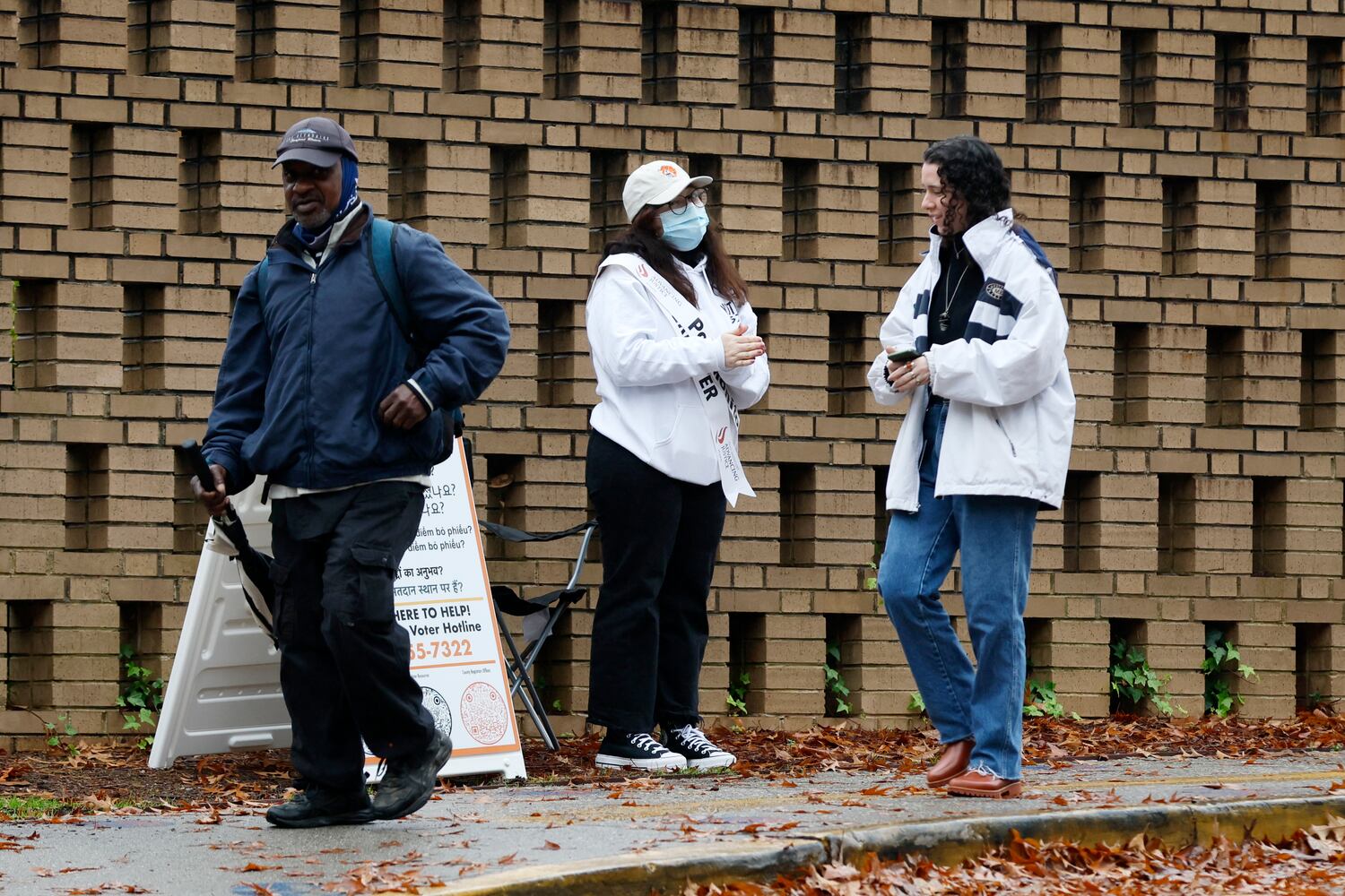 Poll monitor from the Advancing Justice (center) greets voters as they leave the Dresden Elementary School during election day on Tuesday, December 6, 2022.
 Miguel Martinez / miguel.martinezjimenez@ajc.com