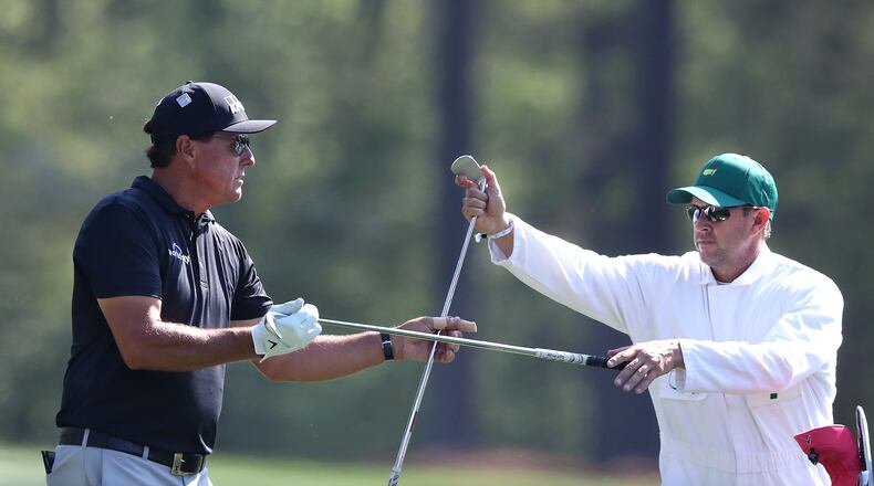 Phil Mickelson changes his club selection with his caddy Tim Mickelson on the 12th tee during his practice round for the Masters at Augusta National Golf Club on Tuesday, April 6, 2021, in Augusta.  Curtis Compton / Curtis.Compton@ajc.com