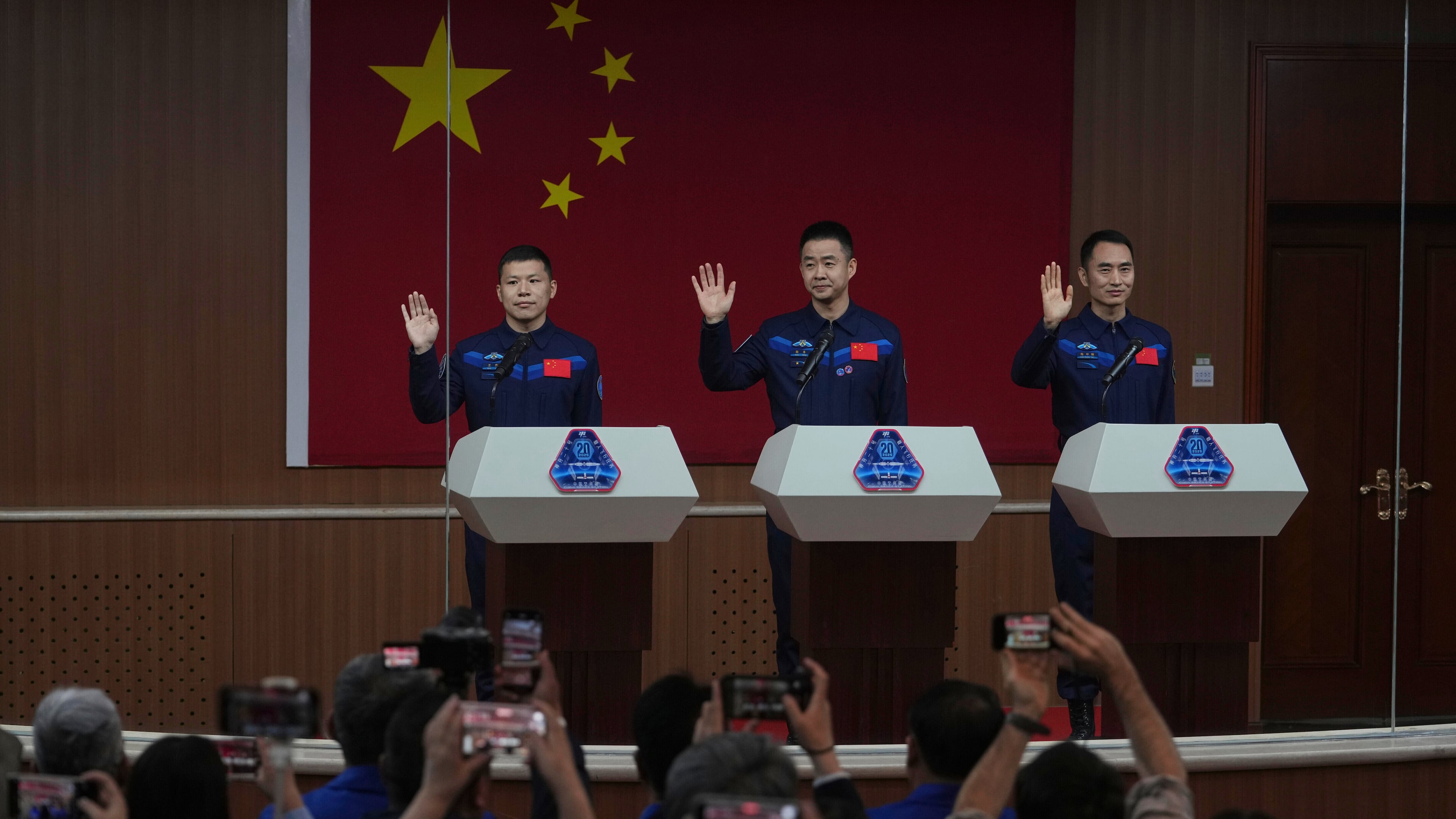 FILE - Journalists film Chinese astronauts for the upcoming Shenzhou 20 mission, from left, Wang Jie, captain Chen Dong and Chen Zhongrui wave at the Jiuquan Satellite Launch Center in northwest China, Wednesday, April 23, 2025. (AP Photo/Andy Wong, file)