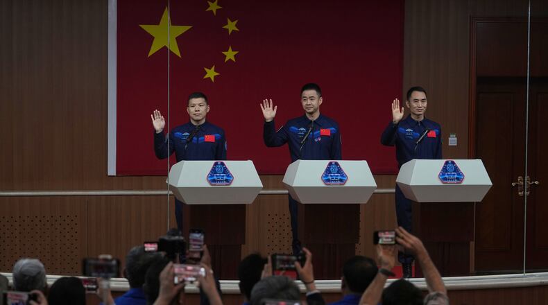 FILE - Journalists film Chinese astronauts for the upcoming Shenzhou 20 mission, from left, Wang Jie, captain Chen Dong and Chen Zhongrui wave at the Jiuquan Satellite Launch Center in northwest China, Wednesday, April 23, 2025. (AP Photo/Andy Wong, file)