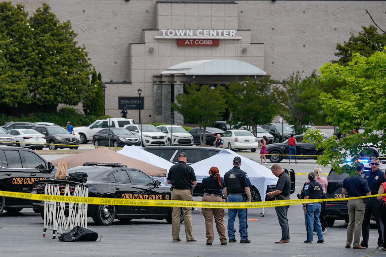 Law enforcement officials gather behind crime scene tape Wednesday afternoon outside the Town Center at Cobb amid a shooting investigation. (Ben Hendren for the AJC)