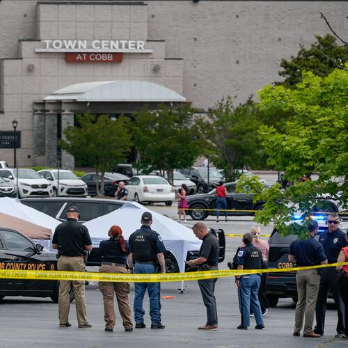 Law enforcement officials gather behind crime scene tape Wednesday afternoon at the Town Center at Cobb amid an officer-involved shooting investigation. (Ben Hendren for the AJC).