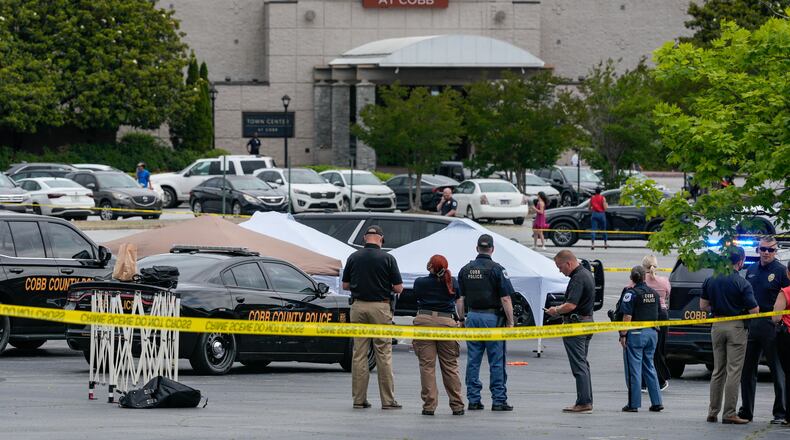 Law enforcement officials gather behind crime scene tape Wednesday afternoon at the Town Center at Cobb amid an officer-involved shooting investigation. (Ben Hendren for the AJC).